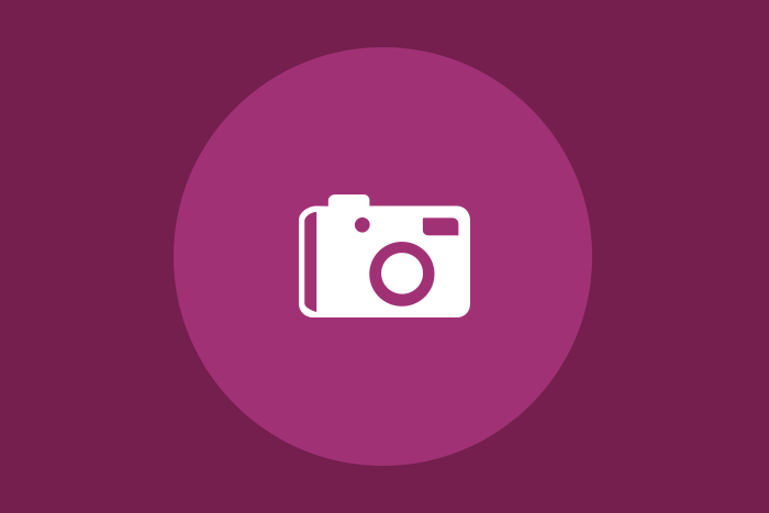 Icono grande donde se muestra en color blanco una cámara fotográfica dentro de un fondo rosa mexicano.